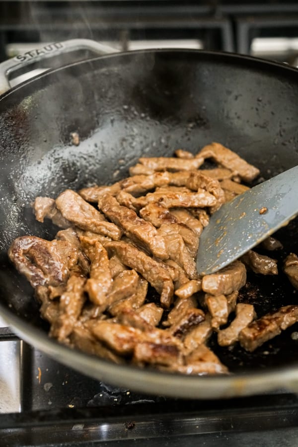 Stir frying sliced beef in the wok