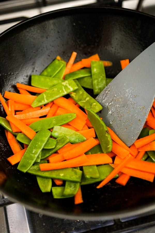 Stir frying carrots and snap peas on wok