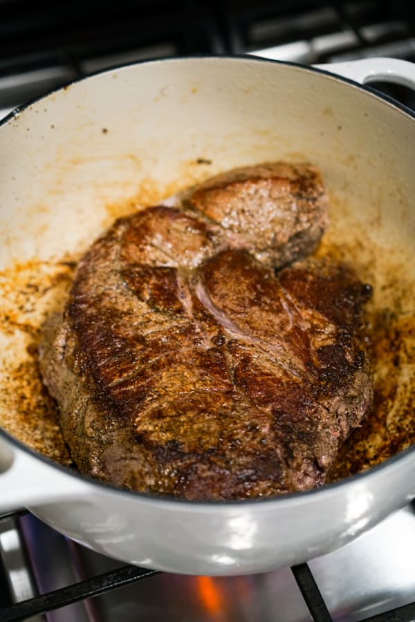 A large piece of beef chuck in Dutch oven on stovetop