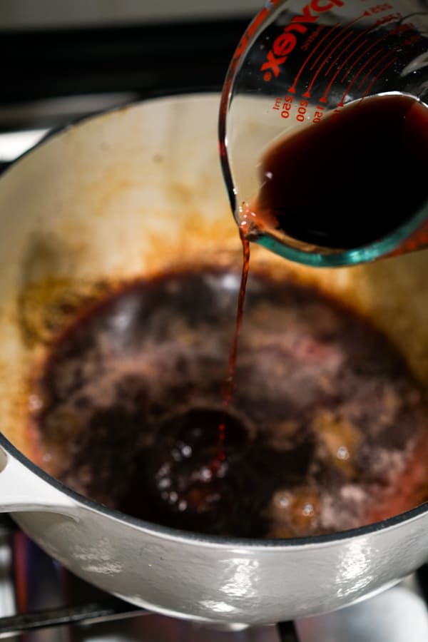 Pouring red wine into Dutch oven