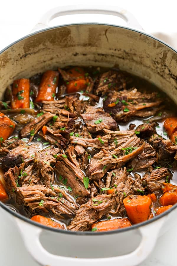 A white pot of shredded pot roast