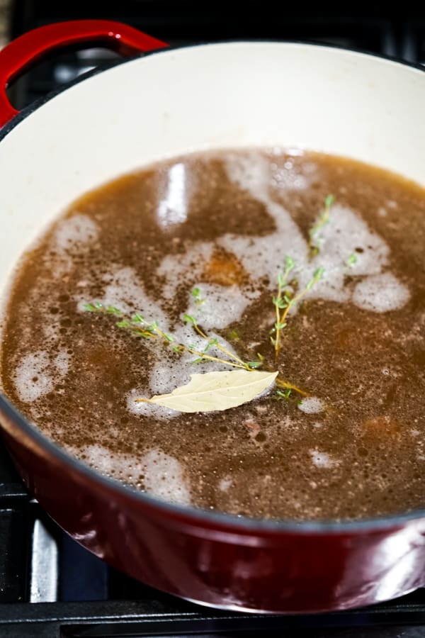 Beef broth with herbs in a red Dutch oven