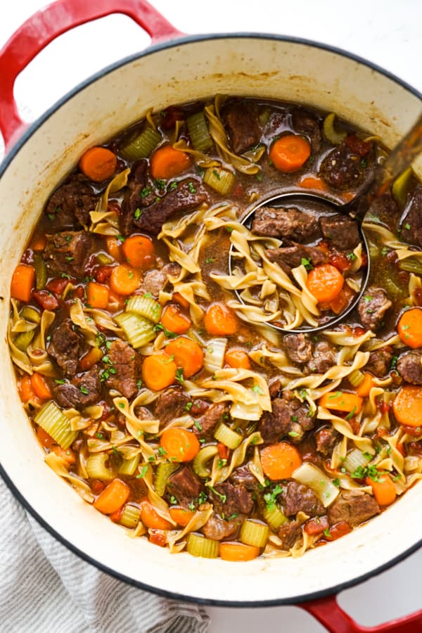 A pot of Beef noodle soup, with a ladle scooping some out