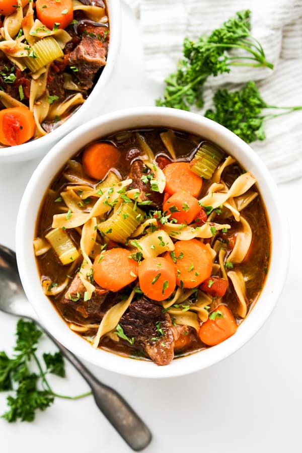 Top down view of a bowl of Beef Noodle Soup, spoon on the side