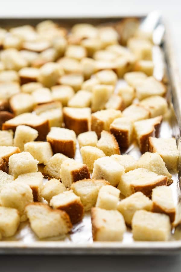 Unbaked cubed bread on a baking sheet lined with aluminum foil