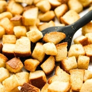 Using spatula to scoop some crispy croutons up from the baking sheet