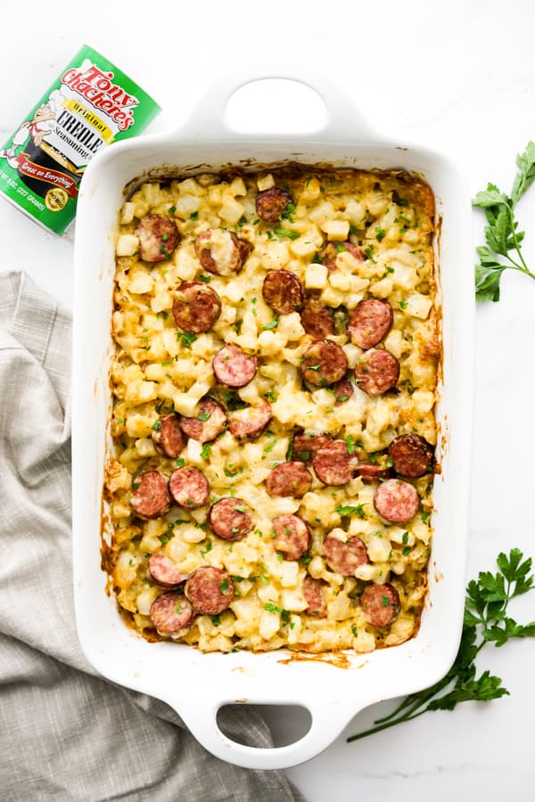 Top down view of potato casserole with andouille sausage, with creole seasoning on the side