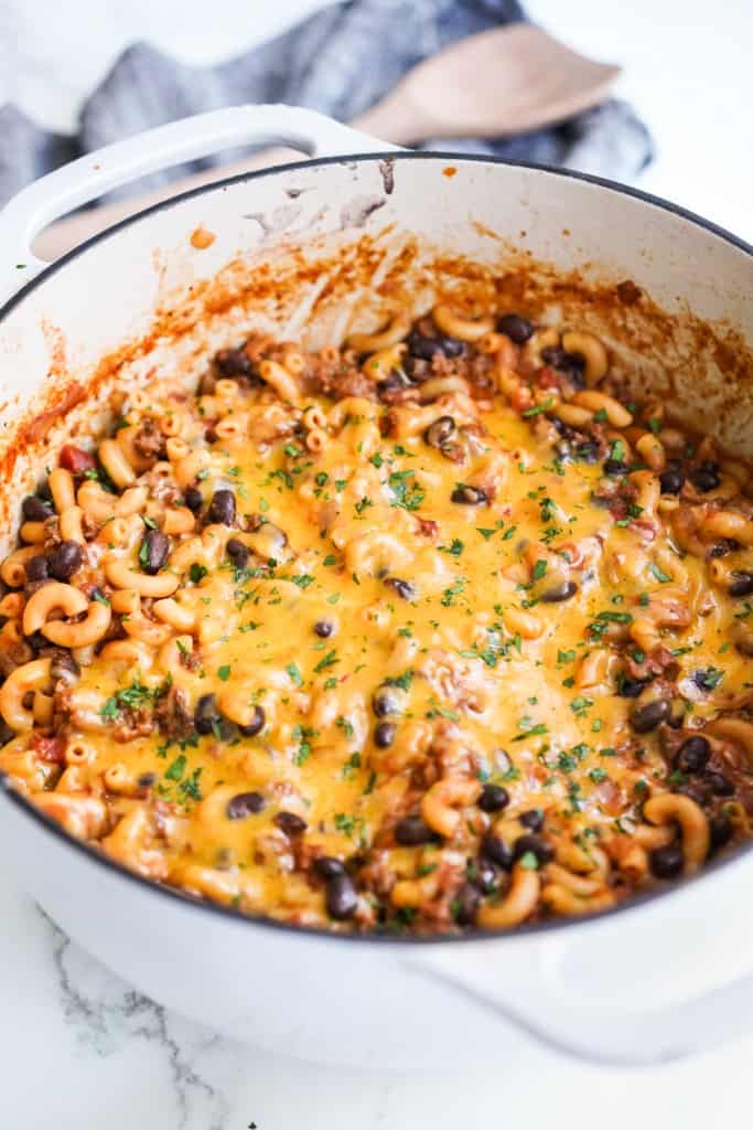 Thick and chucky chili mac in a pot with melted cheddar cheese on top