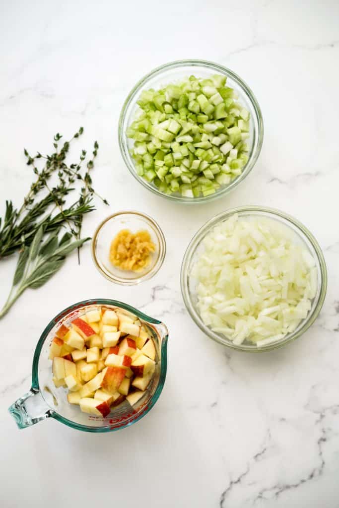 Herbs, bowls of celery, onions, garlic and apples