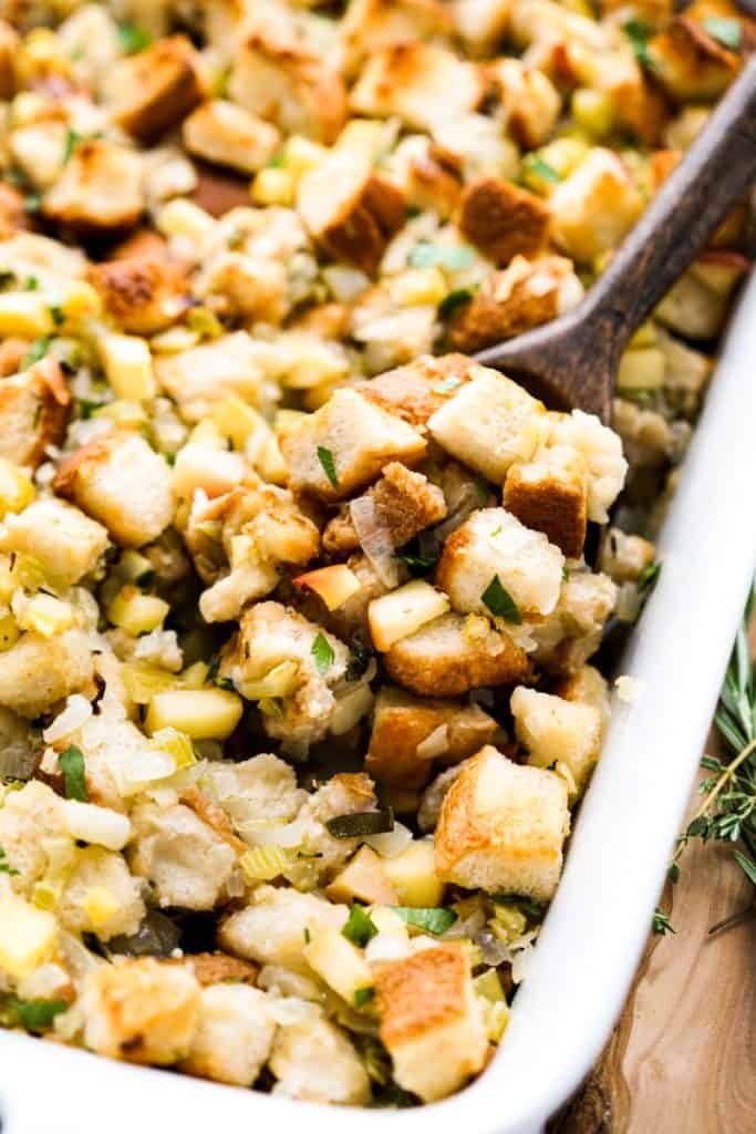 Closeup of a brown spoon digging into a dish of apple stuffing