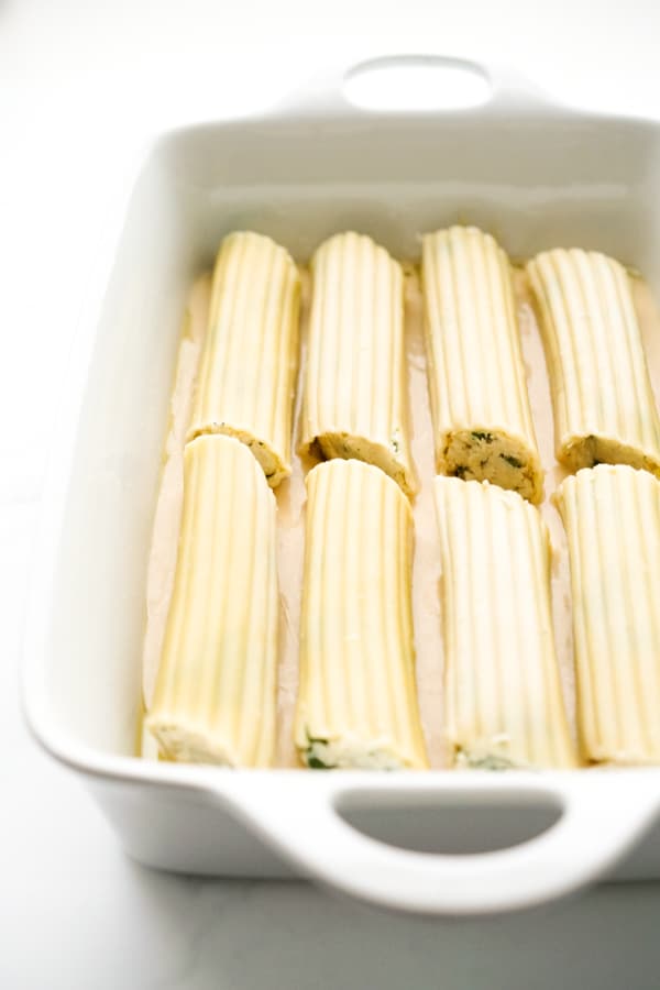 8 unbaked stuffed manicotti in a baking dish