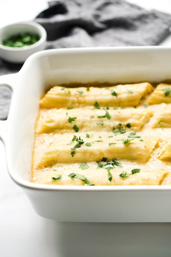 Tubes of stuffed manicotti smothered in ALfredo sauce and cheese in a casserole dish