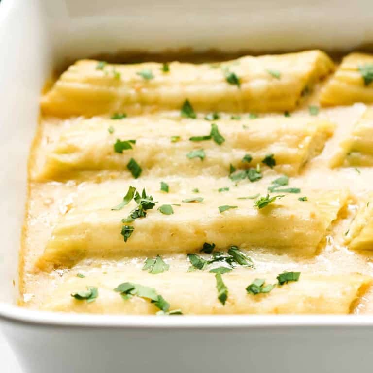 Manicotti in white sauce lined up in a dish