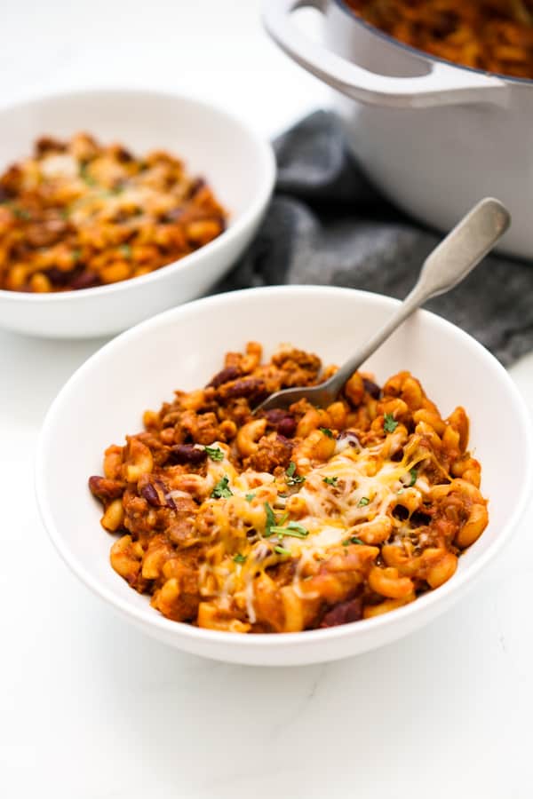 A bowl of macaroni in chili cheese sauce topped with more cheese