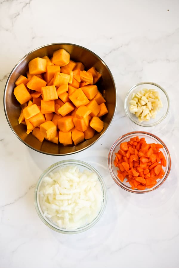 Bowls of cubed butternut squash, minced garlic, chopped carrots and diced onions