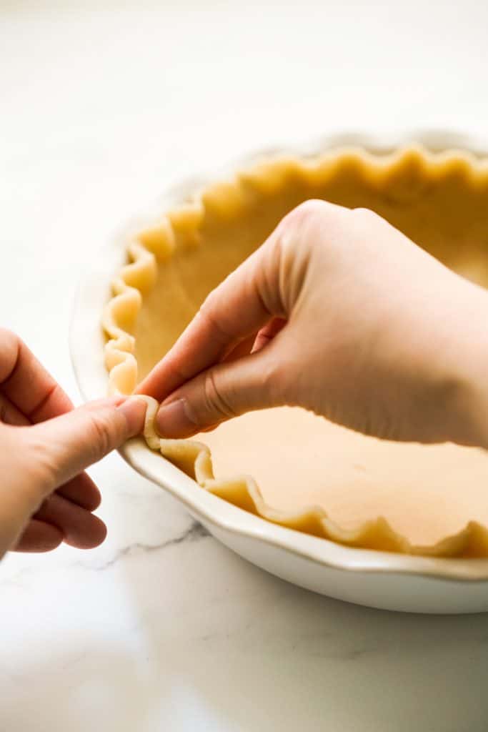 Crimping the sides of the unbaked pie crust dough