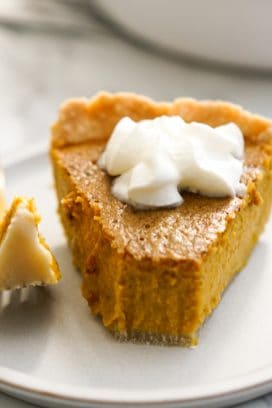 a half eaten slice of pumpkin pie with whipped cream