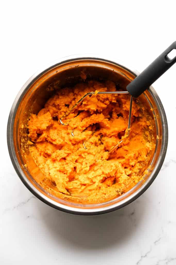 Using a potato masher to mash sweet potatoes