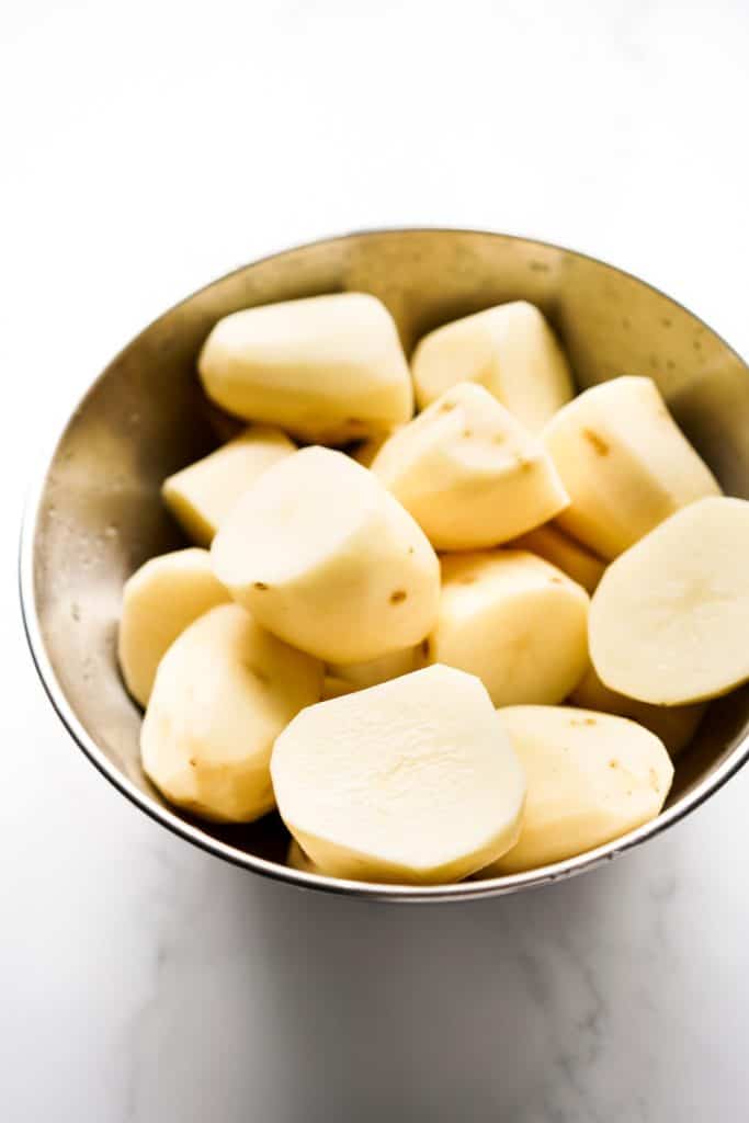 A bowl of peeled potatoes in large chunks