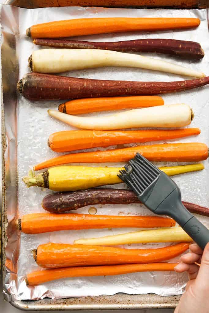 Brushing oil and seasoning onto whole carrots