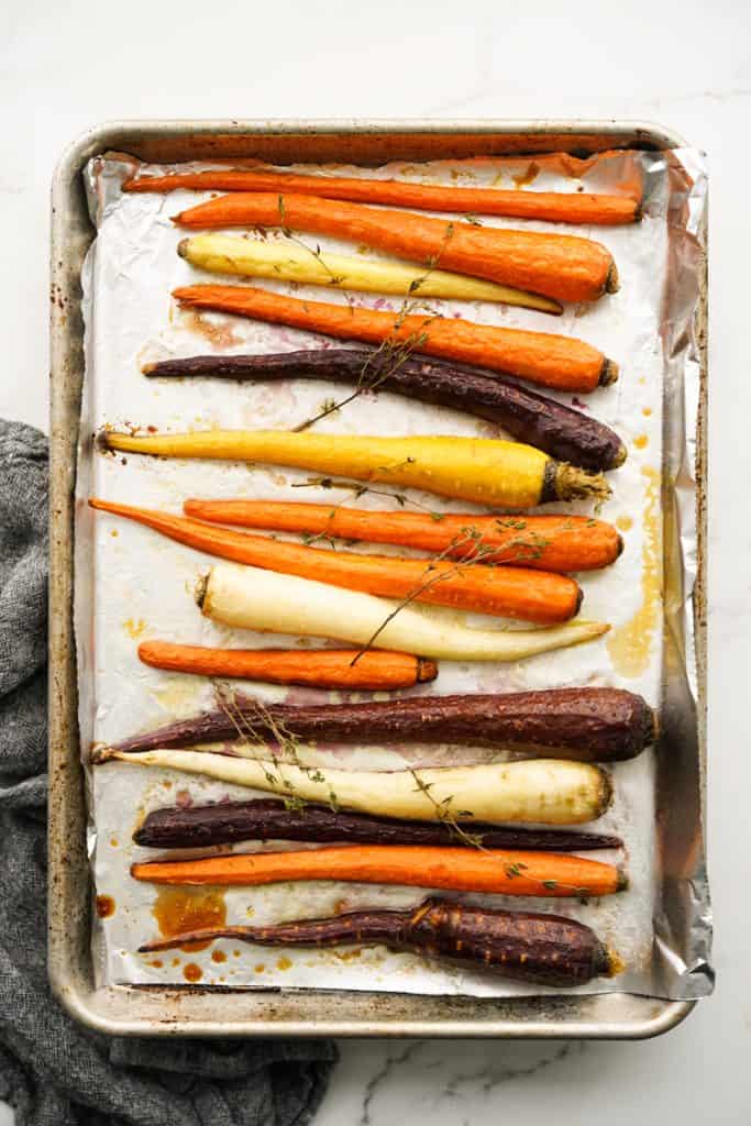 Whole carrots with fresh thyme on top after it has been roasted in the oven