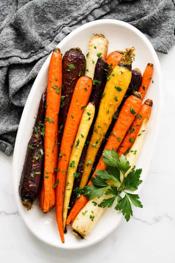 Top down view of an oval plate of colorful whole carrots.