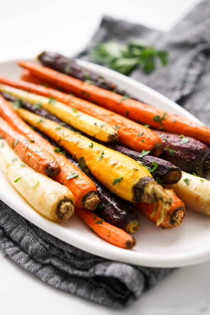 A plate piled with whole roasted carrots in various colors