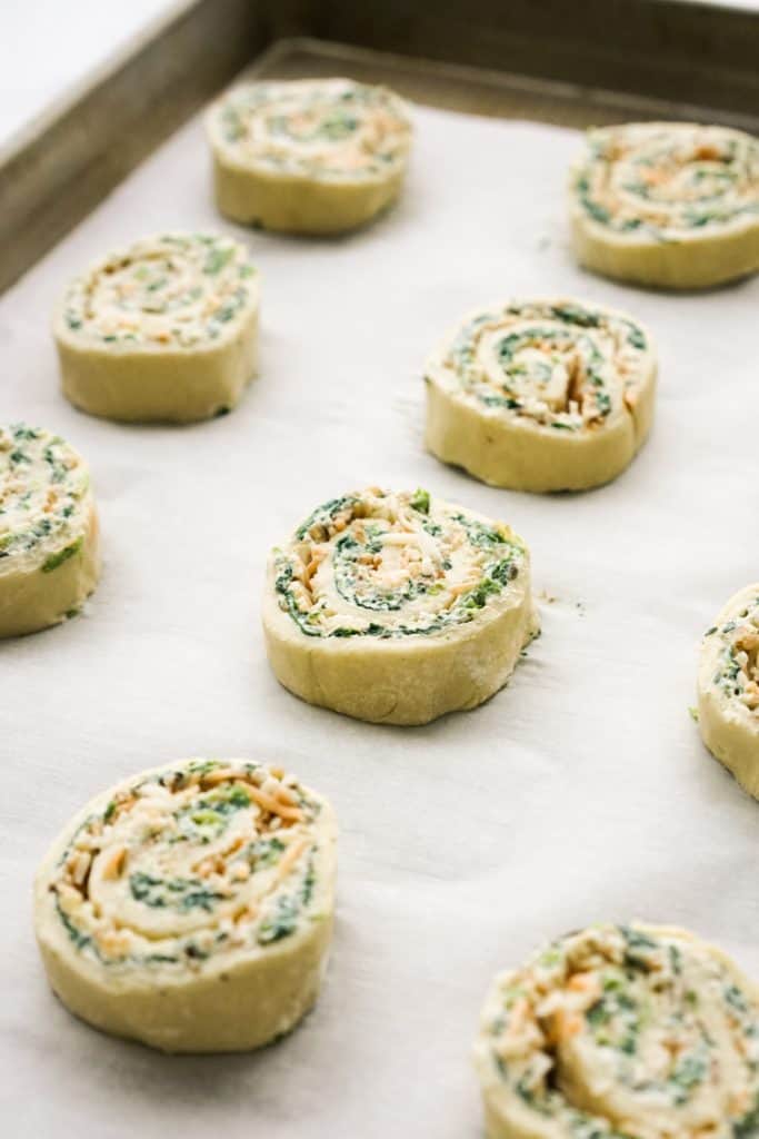 unbaked spinach pinwheel on baking sheet