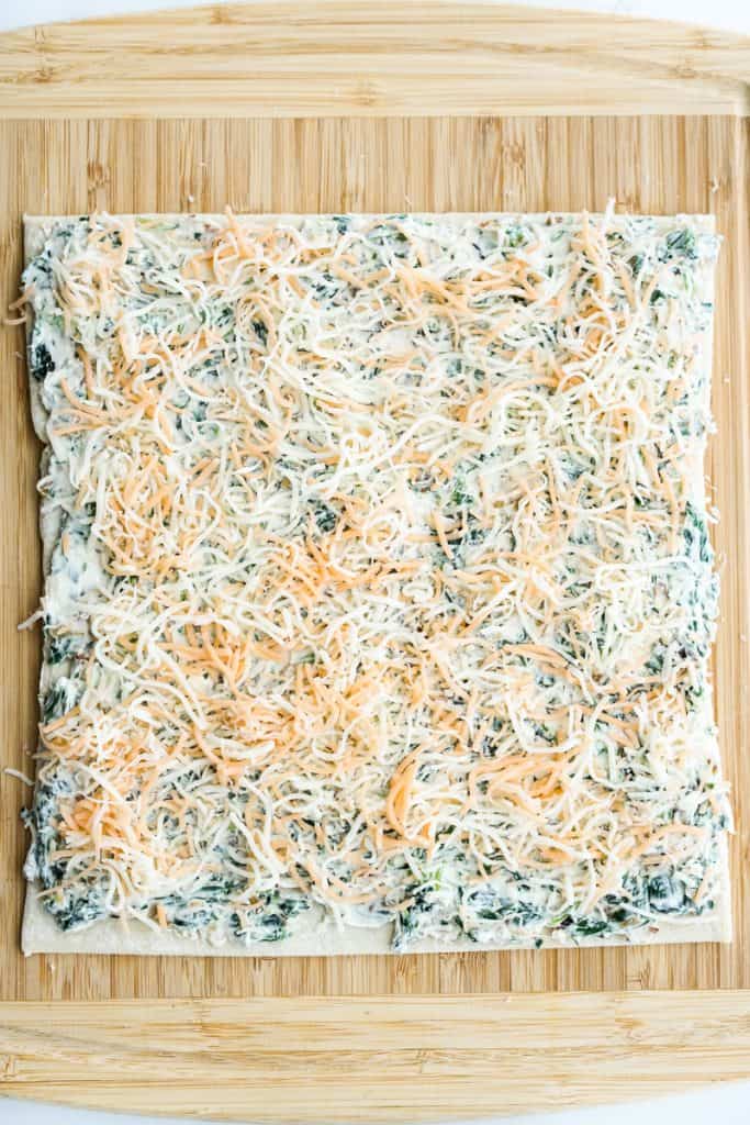 Puff pastry sheet topped with spinach cream cheese mixture topped with shredded cheese