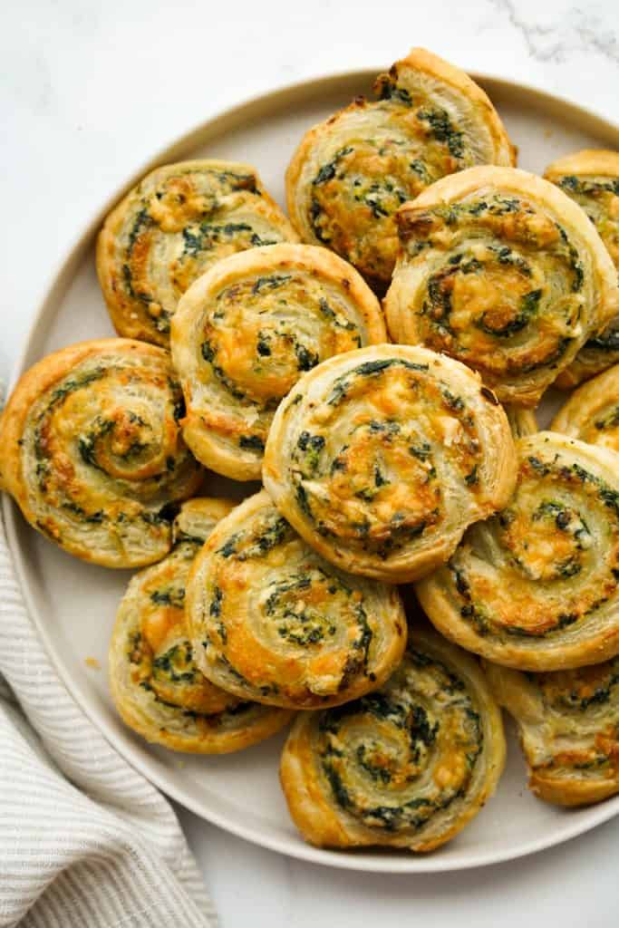 A round plate of spinach pinwheels made with puff pastry