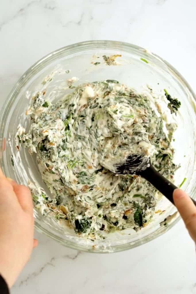 mixing spinach cream cheese mixture in a bowl