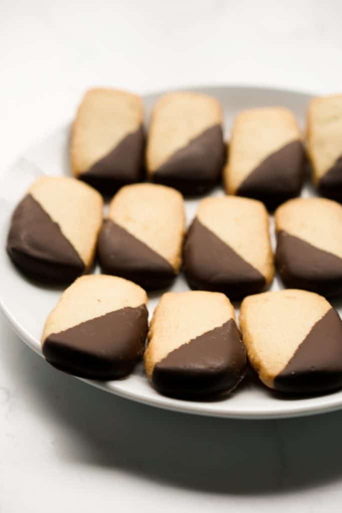 Chocolate dipped shortbread cookies perfectly lined up on a plate