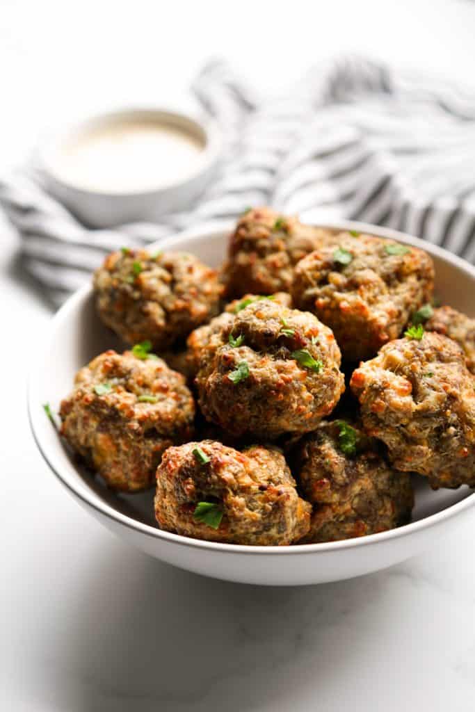 A bowl of cream cheese sausage bowls with dipping sauce in the back ground