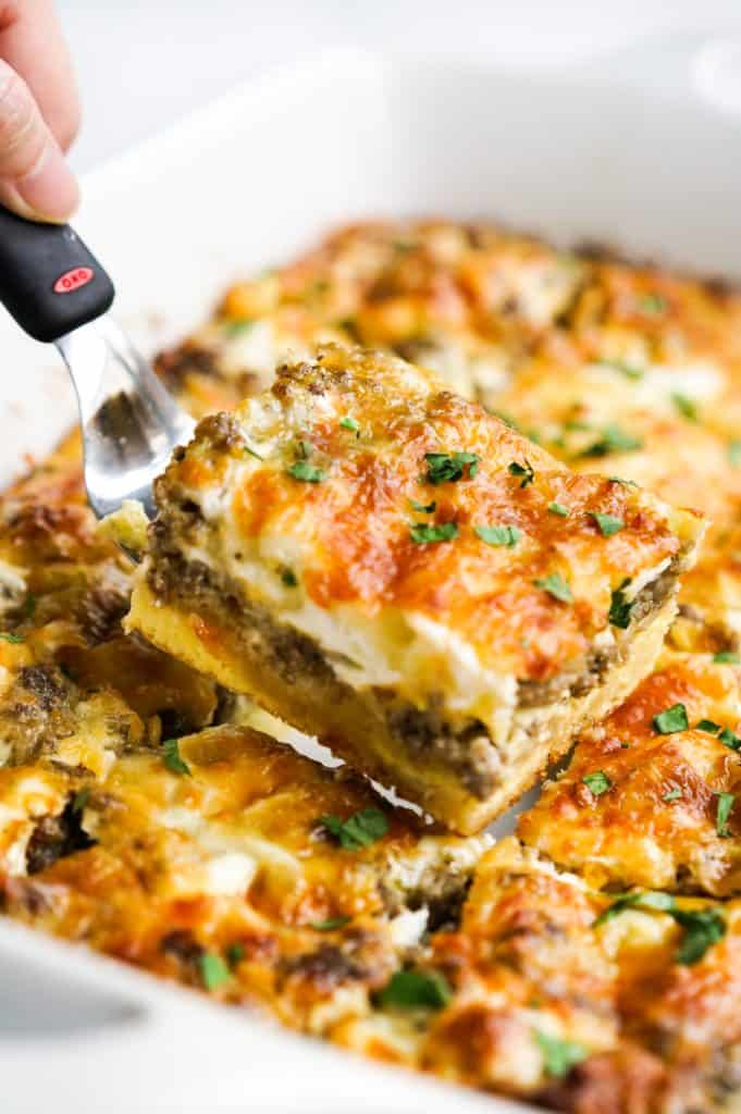 Lifting up a piece of crescent roll breakfast casserole from the dish