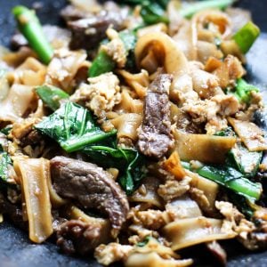 Flat rice noodles tossed with egg, beef and chinese broccoli