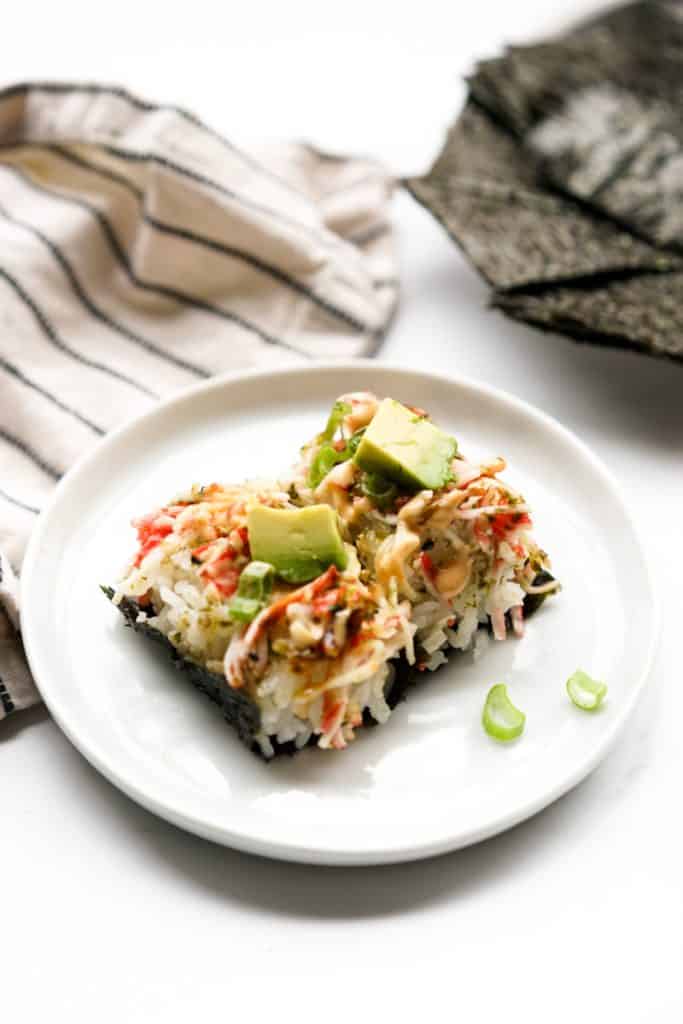 Two pieces of sushi bake wrapped in nori on a small plate