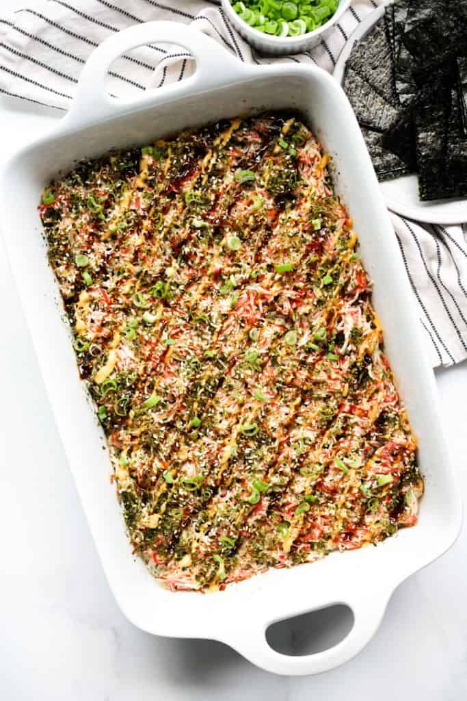 A casserole of sushi bake with nori and green onions on the side