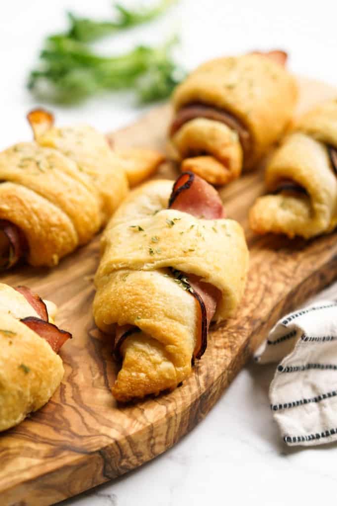 A wooden plater of Ham and Cheese Crescent Roll-ups