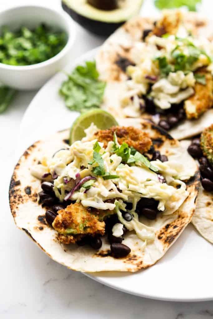 Closeup of avocados, black beans and slaw piled on a tortilla