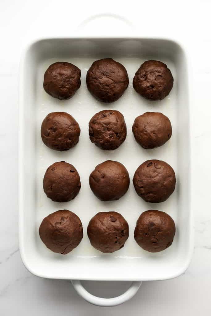 12 chocolate dough balls lined up in rectangular baking dish
