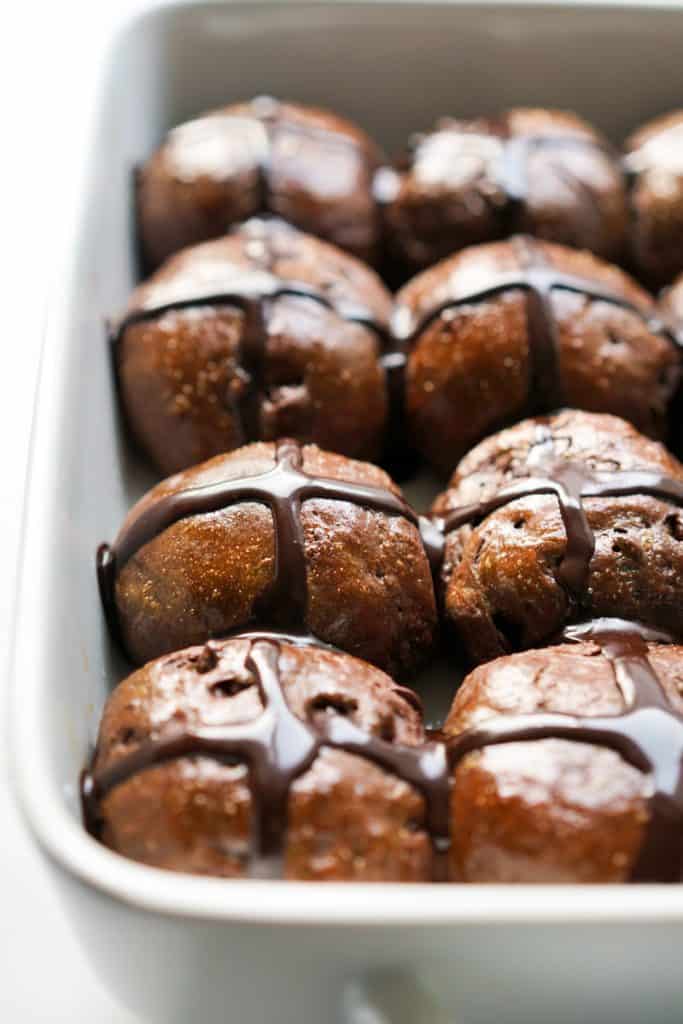 Chocolate hot cross buns loaded with chocolate chips in a baking dish