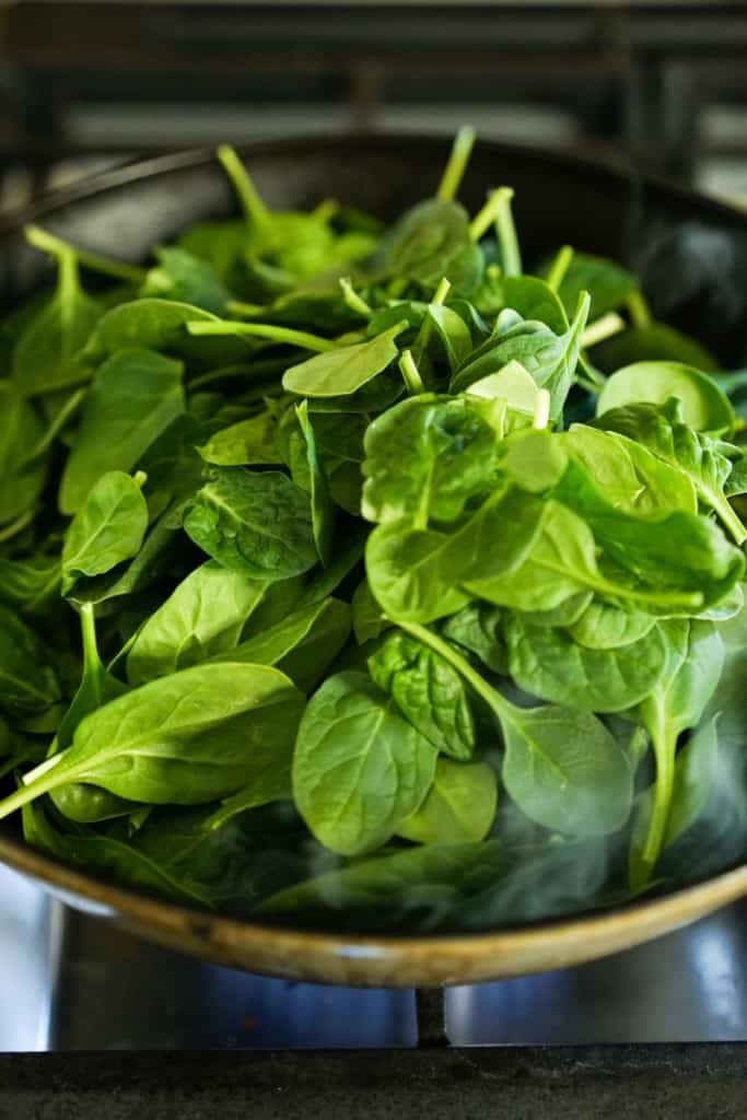 Spinach on a large skillet on stovetop