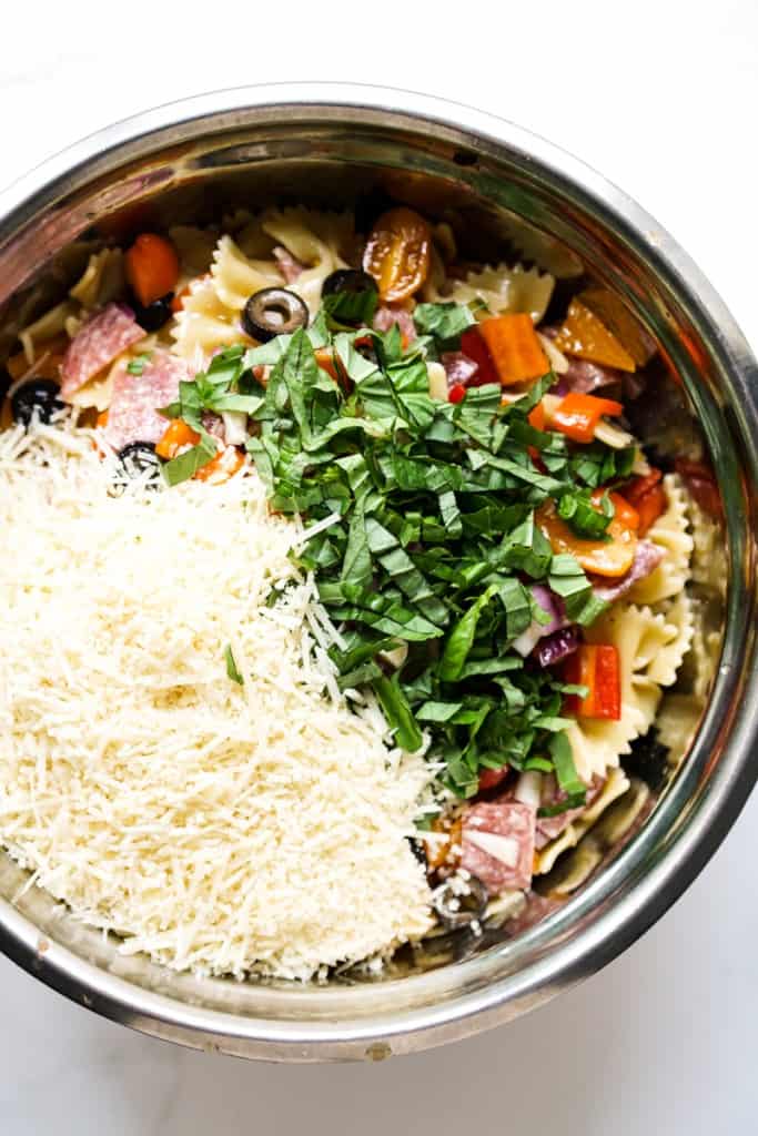A large bowl of bow tie pasta salad topped with parmesan cheese and fresh basil