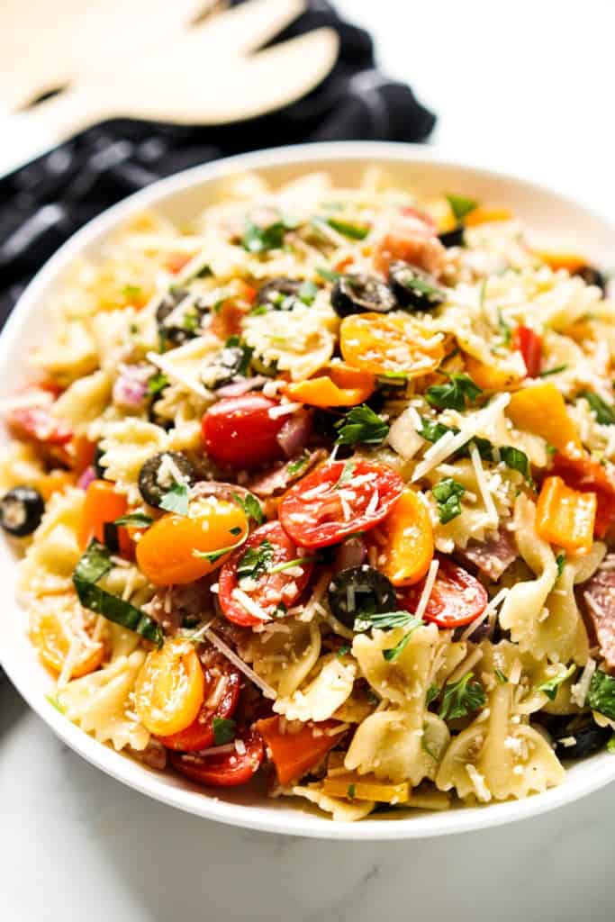 A bowl of bow tie pasta salad loaded with cherry tomatoes, basil and parmesan