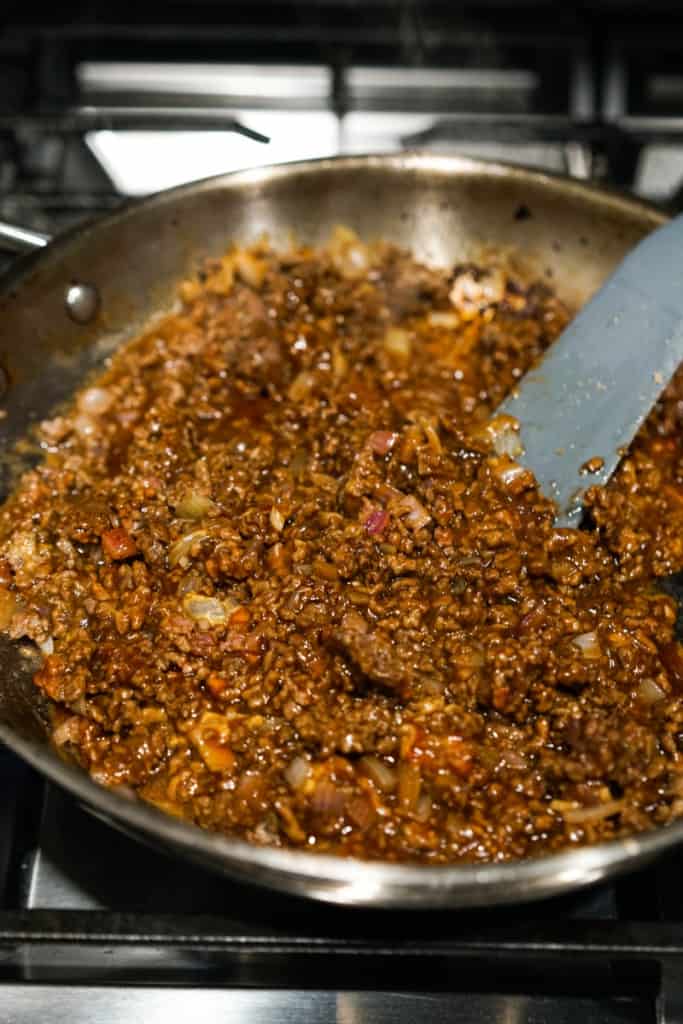 Cooking ground beef with bbq sauce,  ketchup and other sauces and seasonings in a skillet
