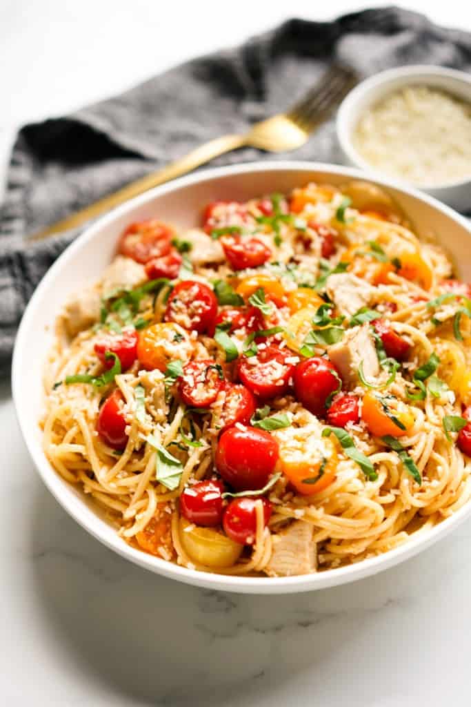 Cherry tomato pasta with cherry in a large bowl, with a bowl of parmesan in the background