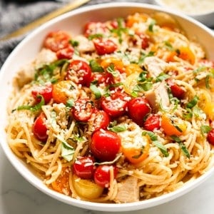 A bowl of cherry tomato pasta with chicken and parmesan dusting on top