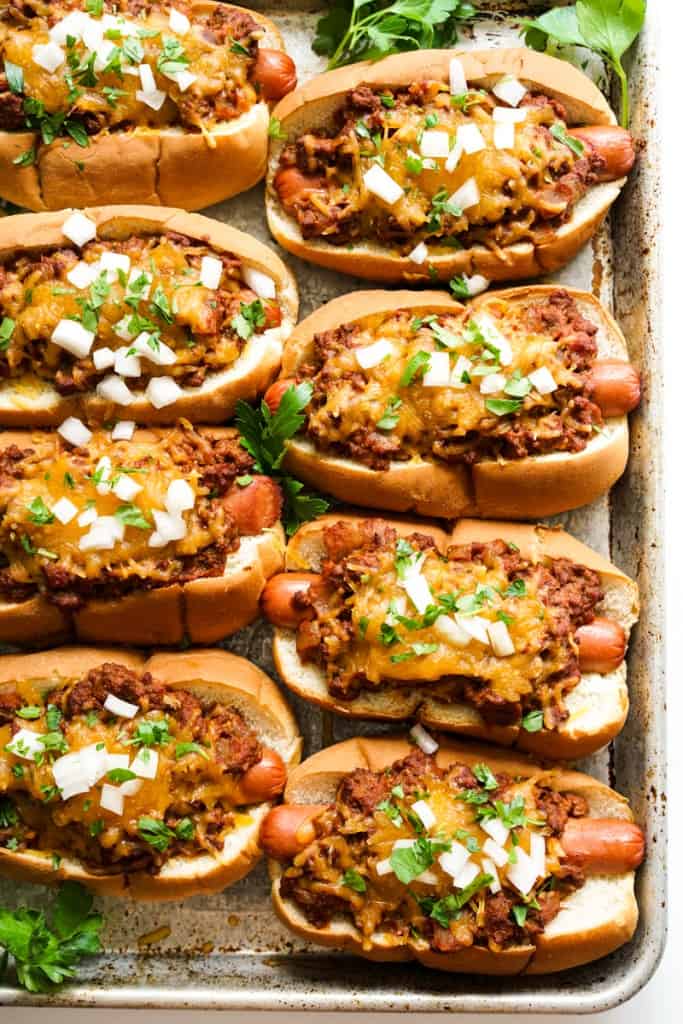 A sheet pan loaded with chili cheese dogs