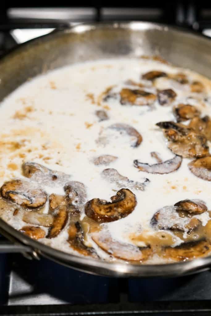 Mushroom, half and half and white wine being cooked on a skillet