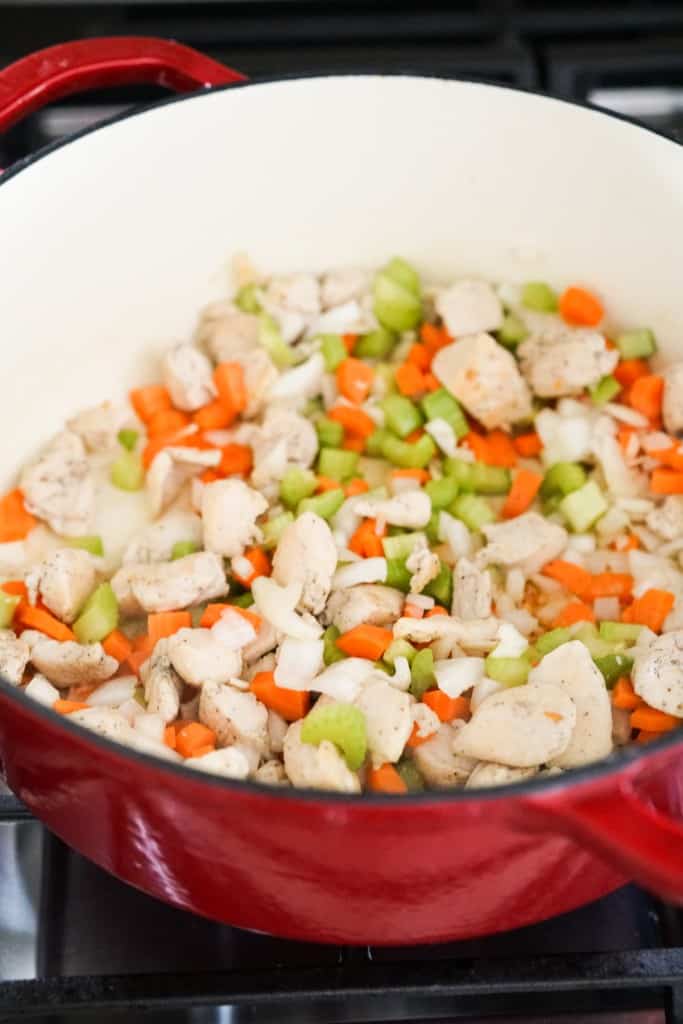 Carrots, celery and onions along with chicken pieces in Dutch oven